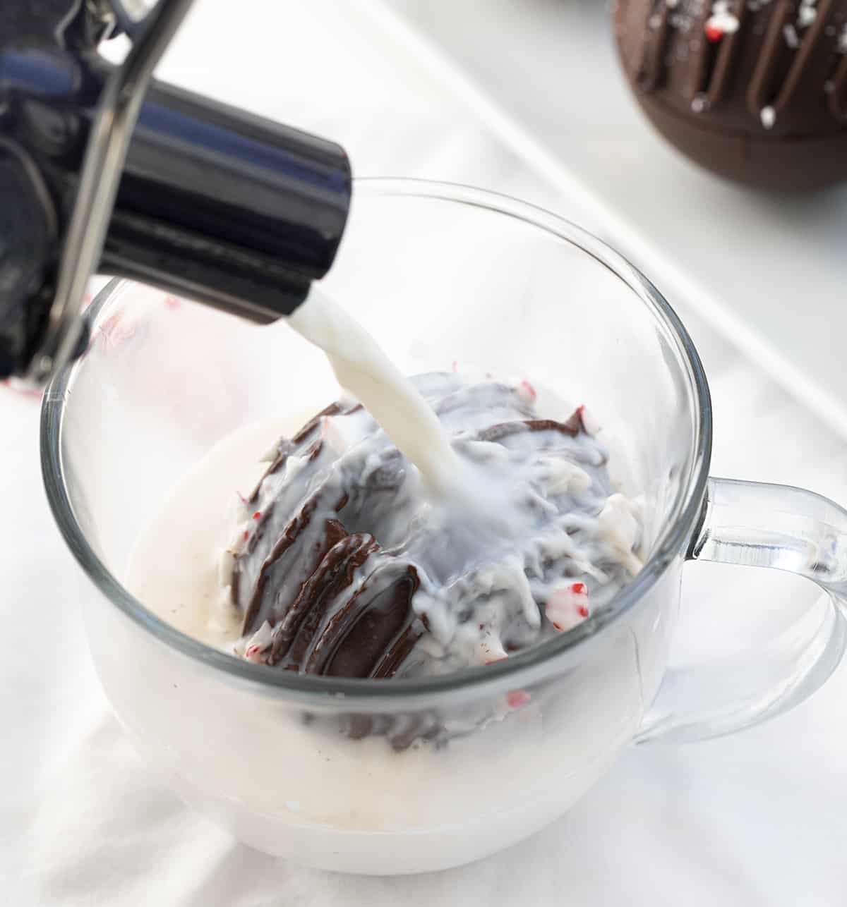 Pouring Hot Milk of a Peppermint Cocoa Bombs.