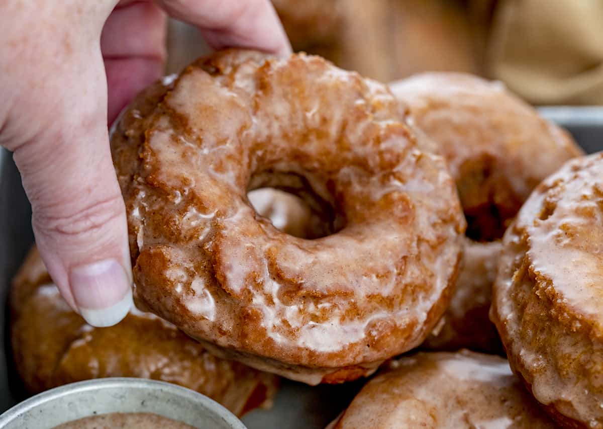 Hand Picking up a Glazed Pumpkin Donut. Breakfast, Donuts, Donut Recipes, Pumpkin Donut Recipes, How to Fry Donuts, Pumpkin Donuts in the Air Fryer, How to Bake Donuts, Baked Pumpkin Donuts, Brunch Ideas, Fall Baking, Best Pumpkin Donuts, i am baker, iambaker