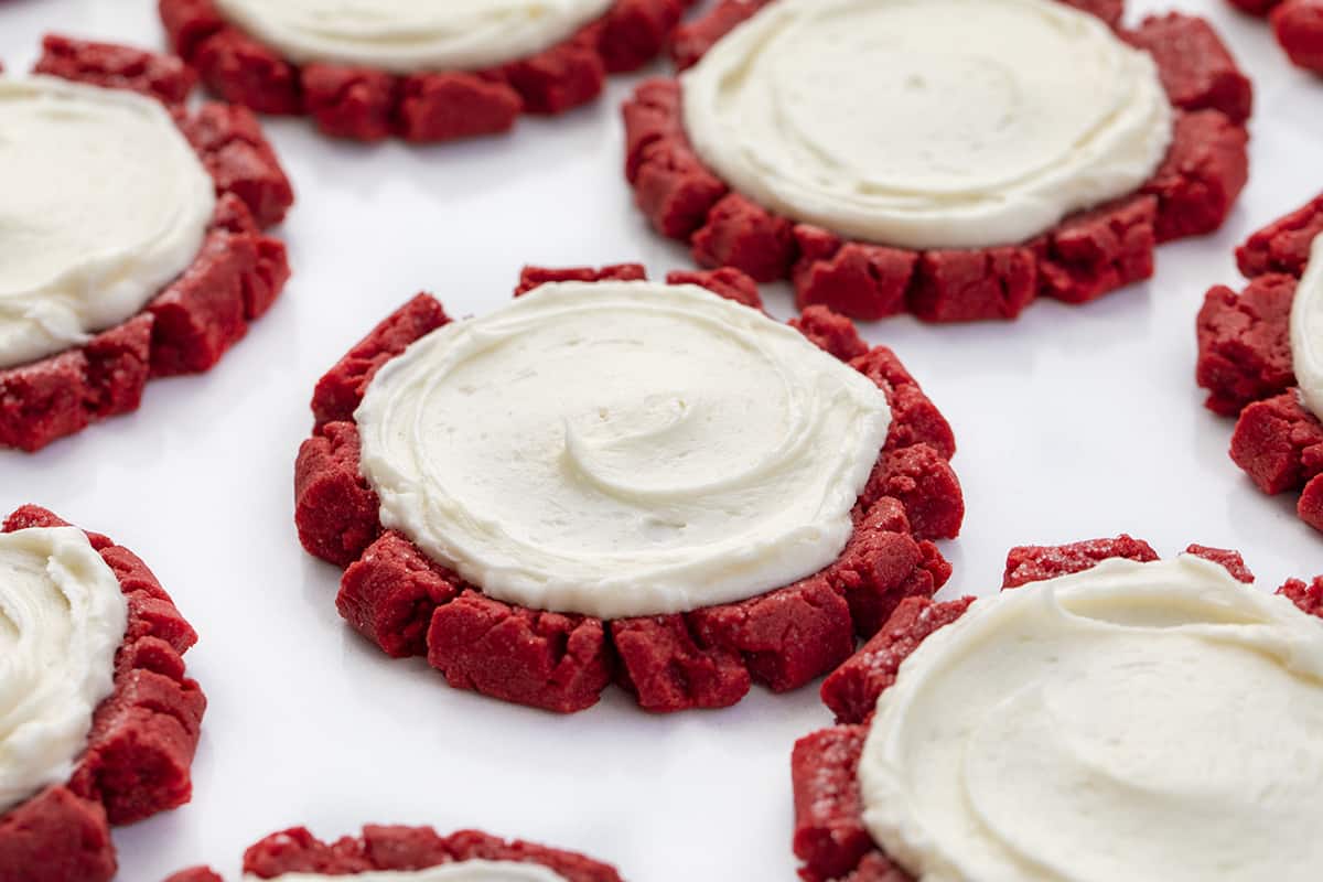 Red Velvet Cookies with Swirled Cream Cheese Frosting on a White Surface. Dessert, Cookies, Baking, Christmas Cookies, Holiday Baking, Cookie Exchange, Red Velvet Recipes, Red Velvet Cookies, Cream Cheese Frosting, Frosted Sugar Cookies, i am baker, iambaker