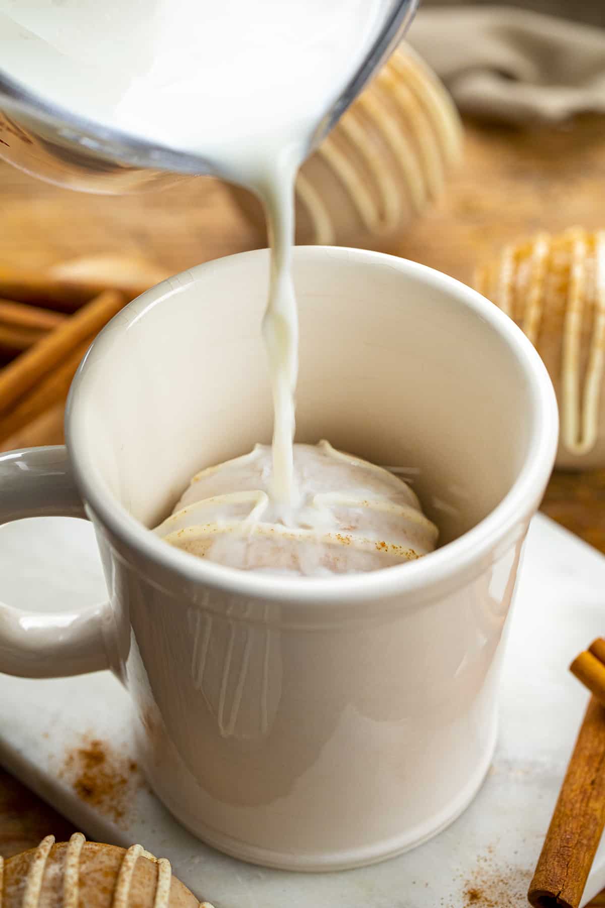 Pouring Milk into a Mug with a Snickerdoodle Hot Chocolate Bomb in it. Hot Chocolate Bomb, Snickerdoodle Hot Chocolate Bombs, How to Make Hot Chocolate Bombs, Best Tasting Hot Chocolate Bombs, How Long Do Hot Chocolate Bombs Last, Hot Chocolate Bombs Near Me, Easy to Make Hot Cocoa Bombs, Best Flavors for Hot Chocolate Bombs, Holiday Dessert, Christmas Chocolate Bombs, Thanksgiving Hot Chocolate Bombs, i am baker, iambaker