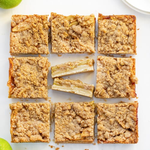 Apple Shortbread Bars on a Counter Cut Into Pieces with the Center Piece Cut Smaller and Flipped on Its Side to Show Bar Layers.