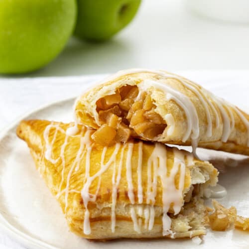 Apple Turnovers on a Plate with One Broken in Half and Apple Filling Spilling Out.