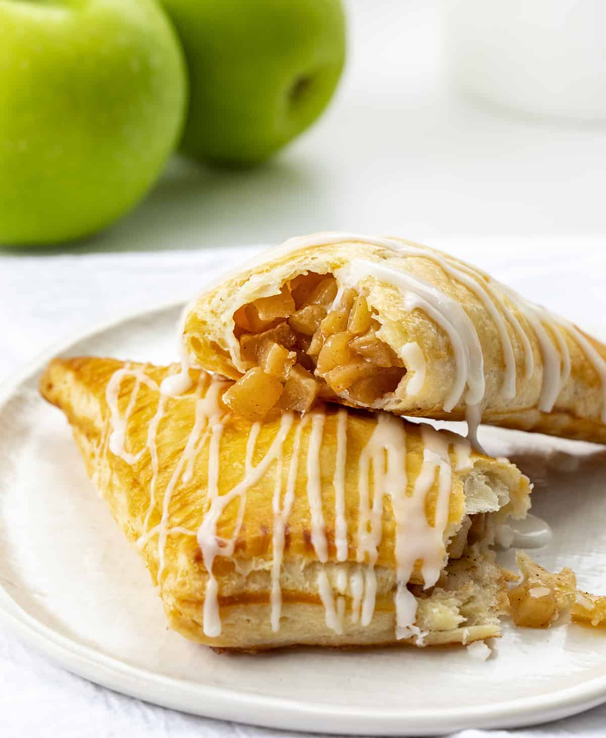 Apple Turnovers on a Plate with One Broken in Half and Apple Filling Spilling Out.
