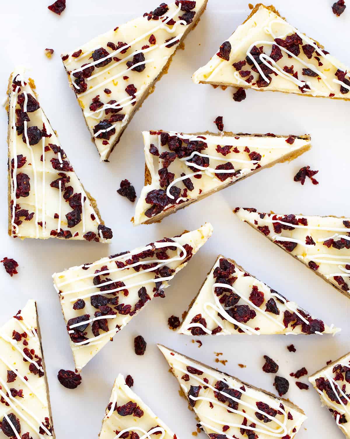 Triangles of Cranberry Bliss Bars Covered in Cream Cheese and Cranberries and Drizzled in White Chocolate.