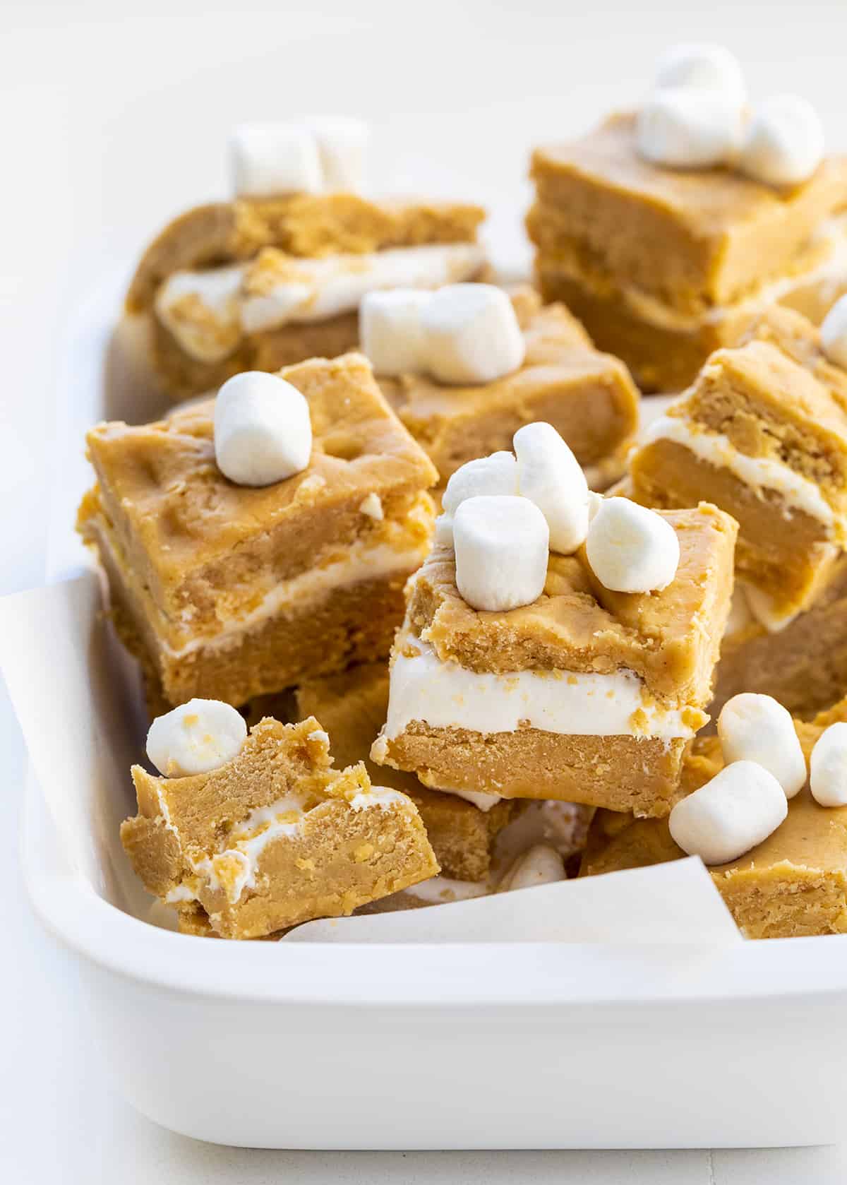 Individual Pieces of Peanut Butter and Marshmallow Fluff Fudge also known as Fluffernutter Fudge in a White Baking Dish and Mini Marshmallows on Top. 