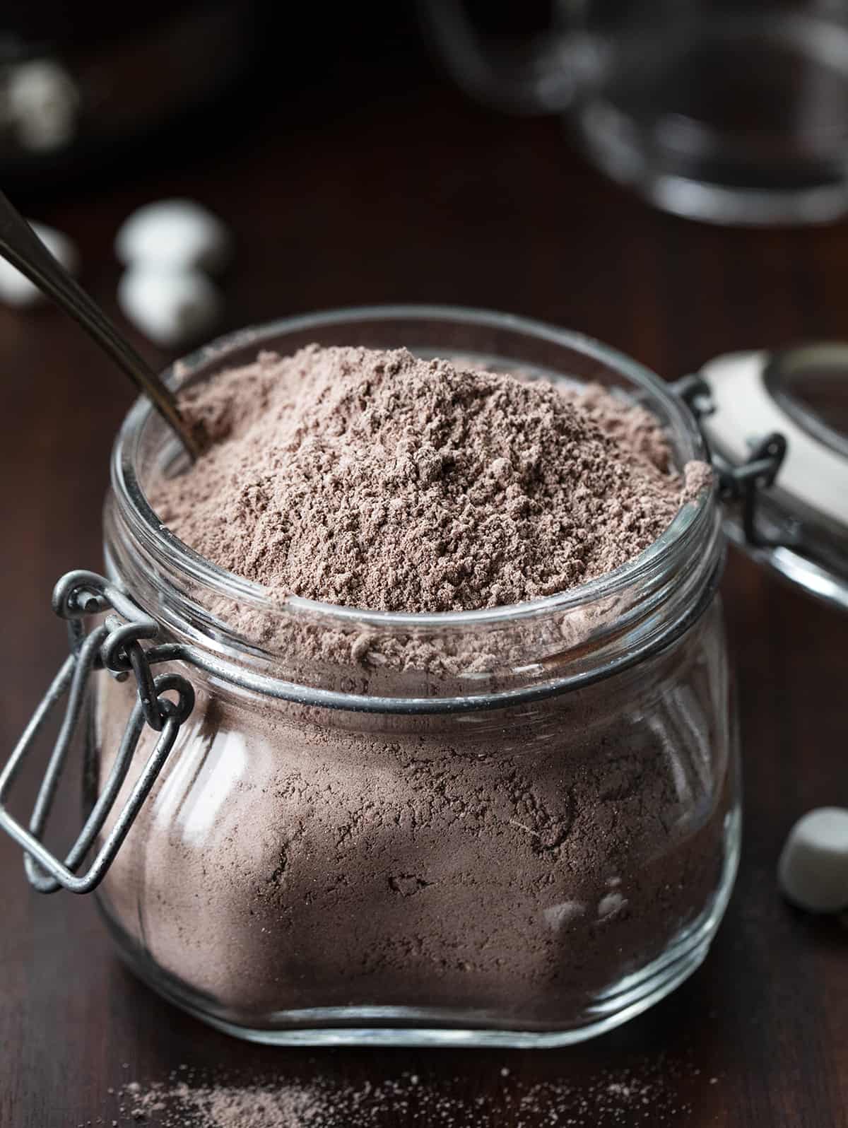 Jar of homemade hot cocoa mix open and with a spoon in it. 