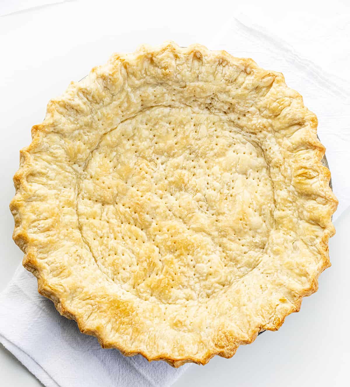 A Baked All Butter Pie Crust in a Pan with No Filling on a White Counter. 