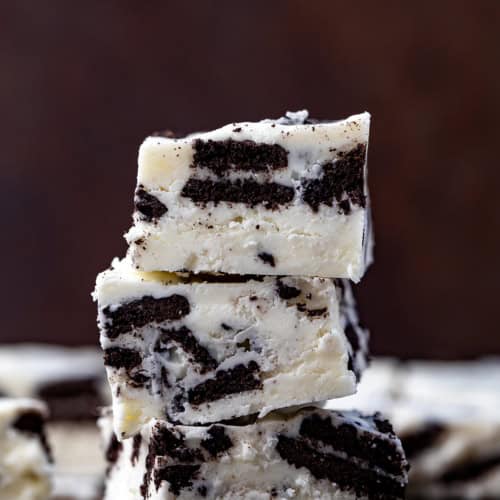 Stack of Cookies and Cream Fudge on a Dark Cutting Board.