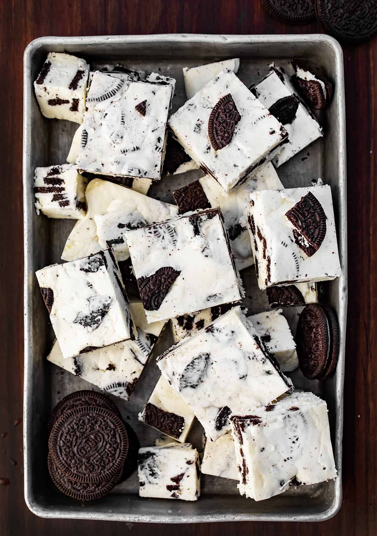 Pan of Cookies and Cream Fudge Cut Into Pieces with Some Oreos Near the Fudge.