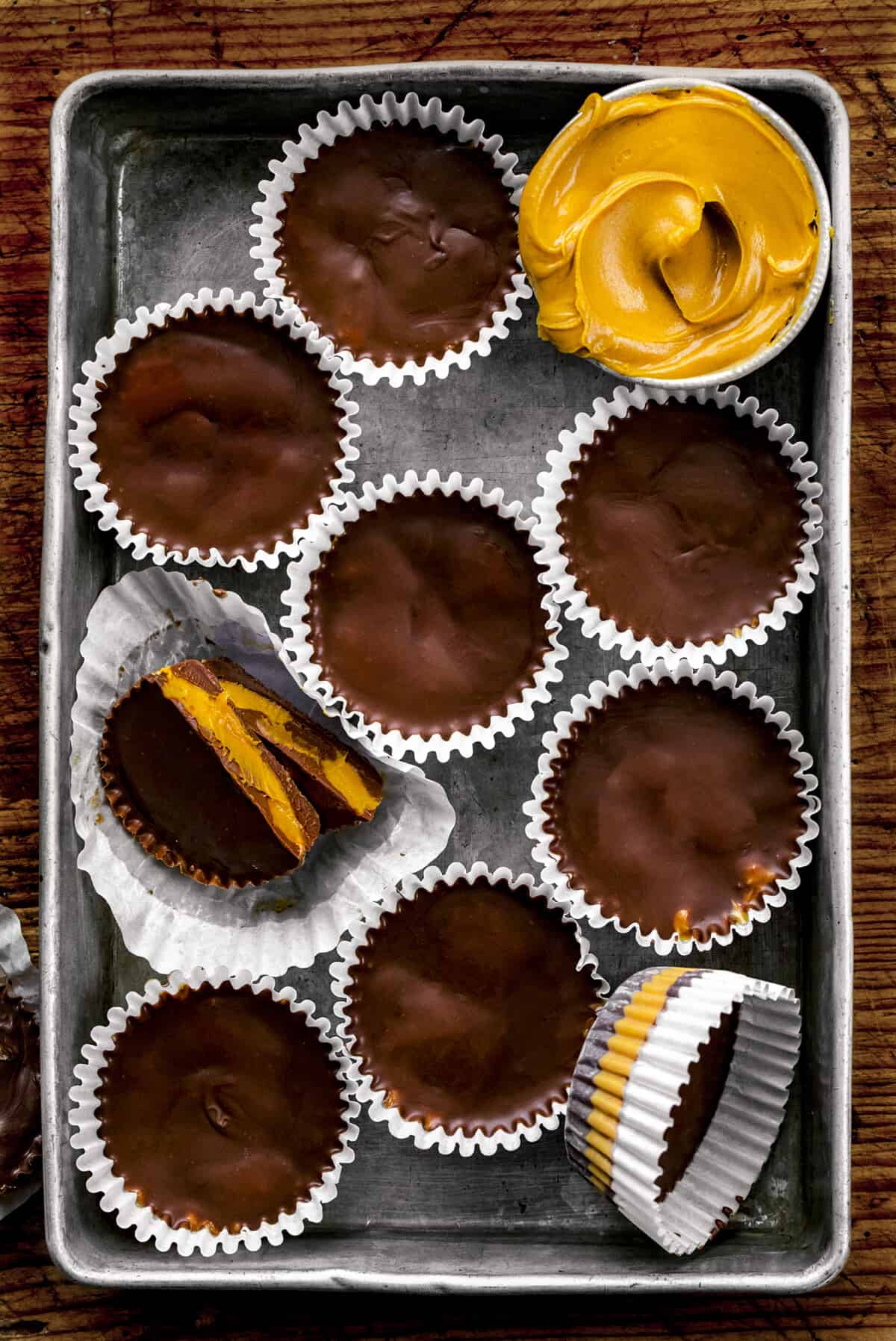 Homemade Peanut Butter Cups in a Pan with Some Extra Peanut Butter and One Cut in Half.
