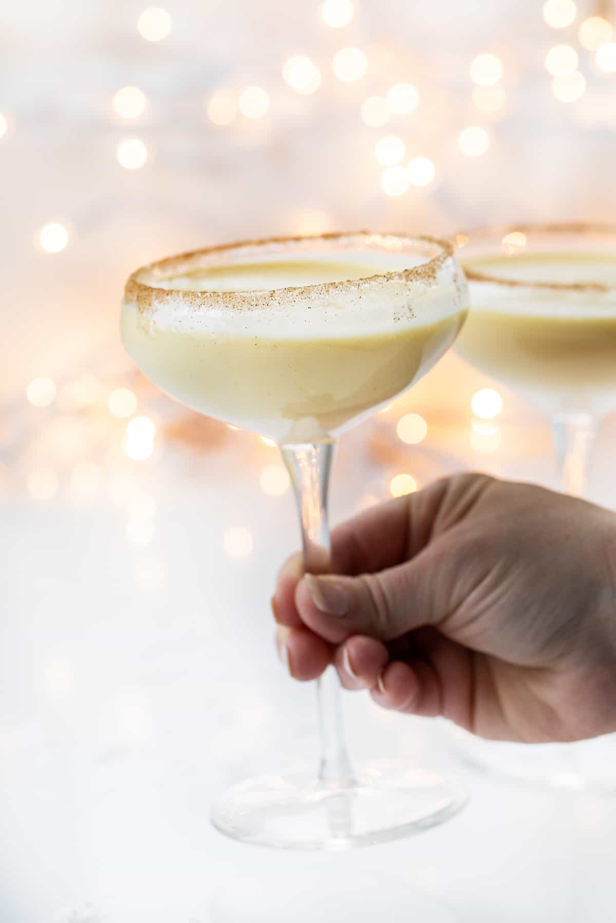 Hand Picking up a Glass of RumChata Eggnog.