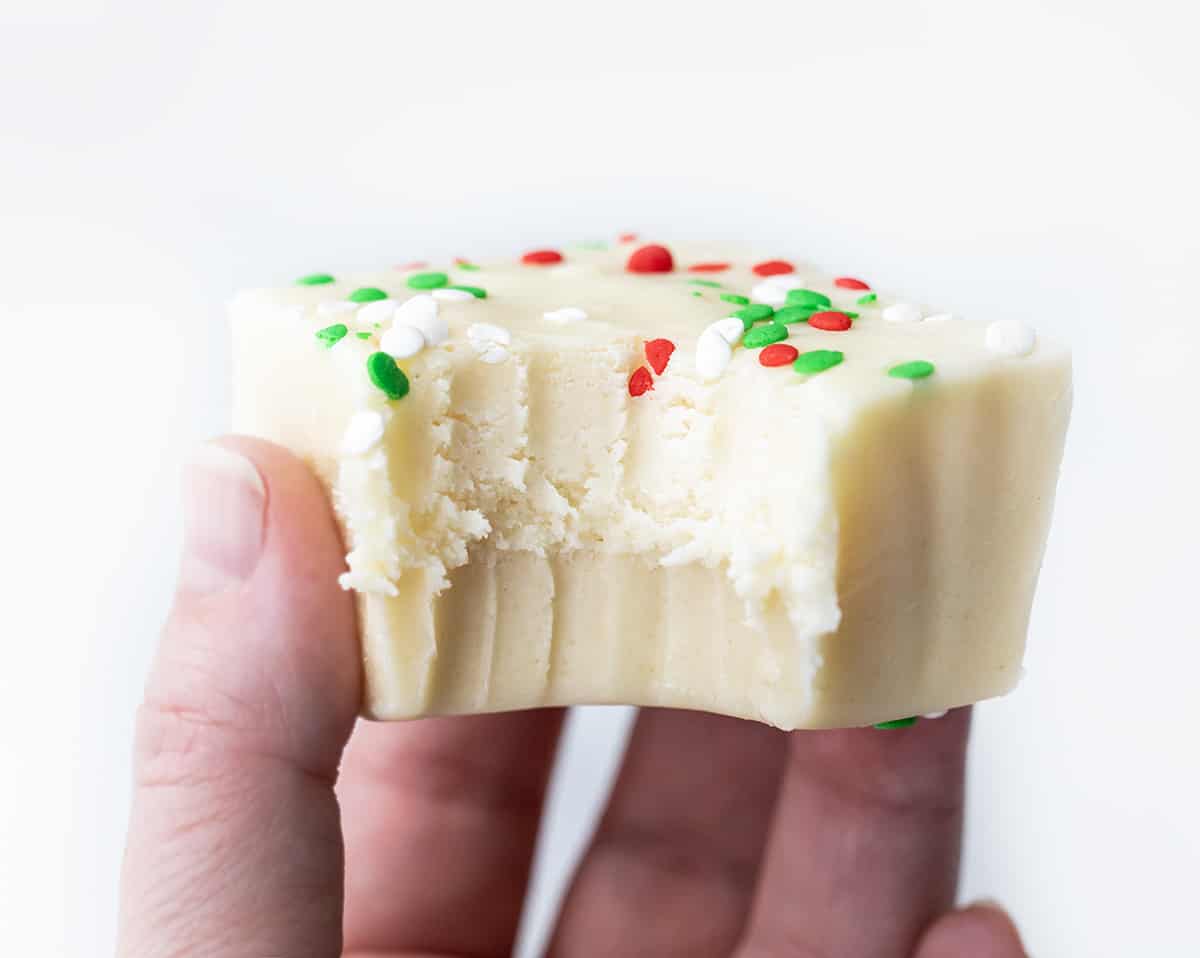 Hand Holding a Piece of Sugar Cookie Fudge with a Bite Taken Out.