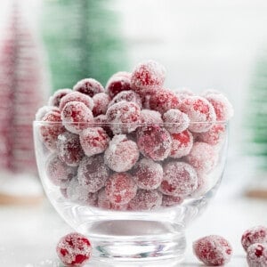 Bowl of Sugared Cranberries with Christmas Decorations in the Background.