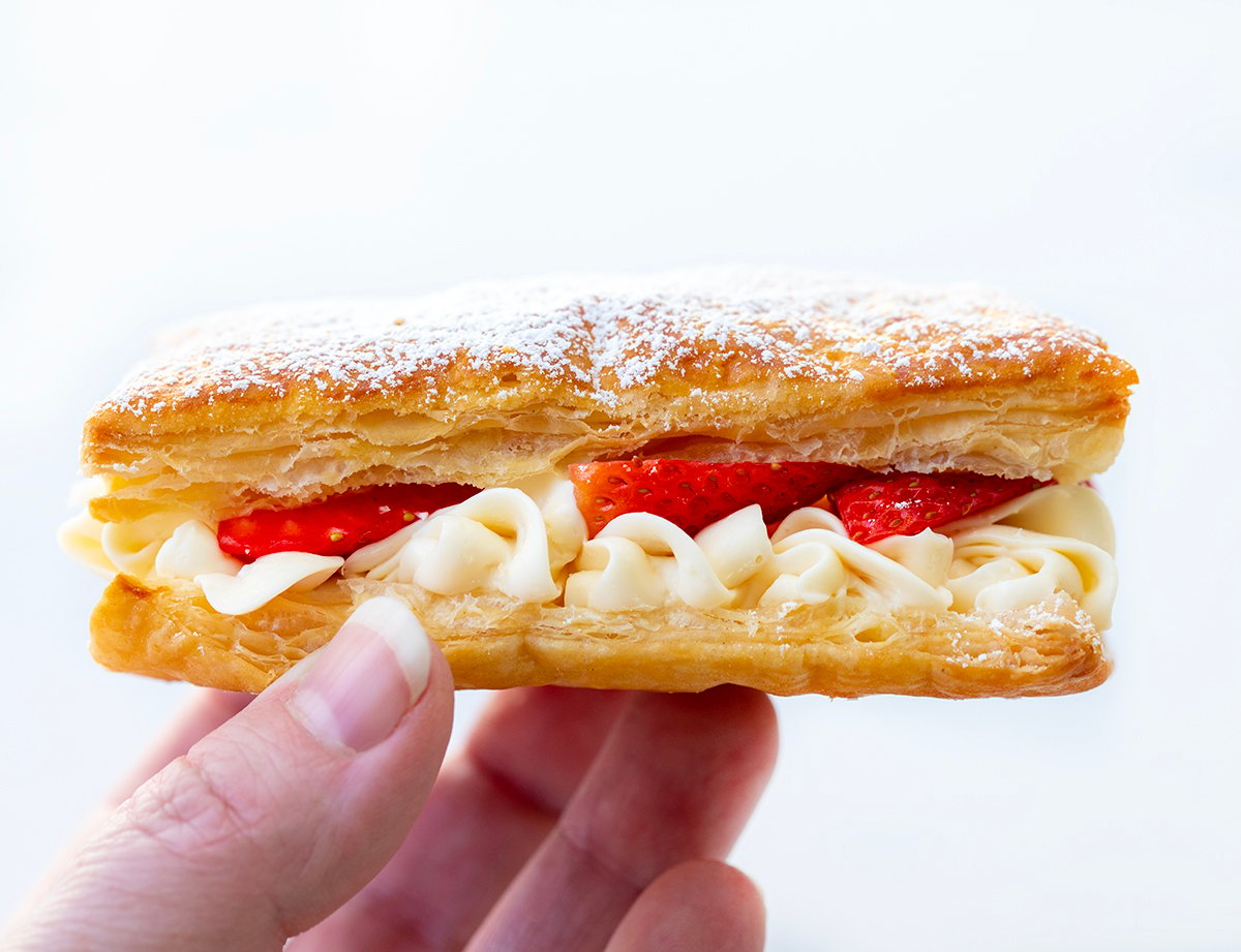 Hand Holding Strawberry Napoleon Showing Cream and Strawberries.