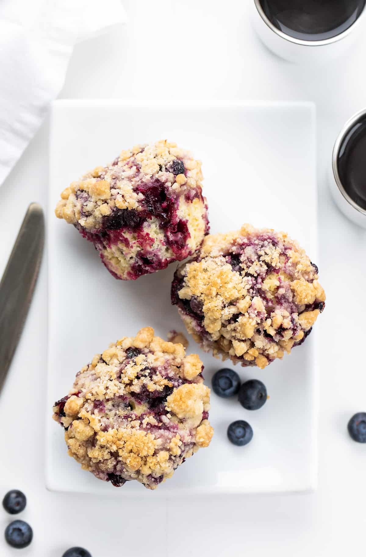 Blueberry Muffins on a White Plate with Blueberries around them.