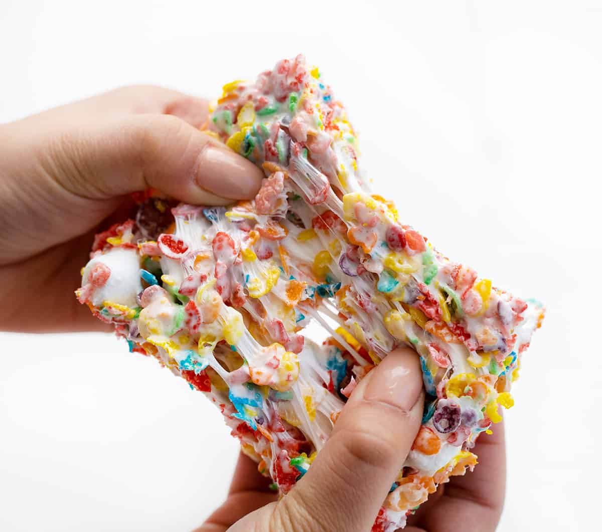 Hands pulling Apart a Soft Fruity Pebbles Treat.