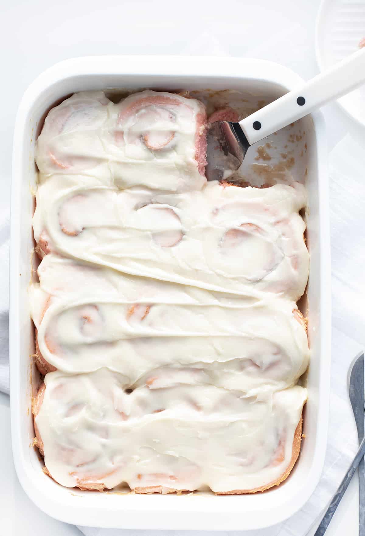 Pink Rolls in a pan with frosting. Cinnamon roll make with heavy cream and tinted pink.