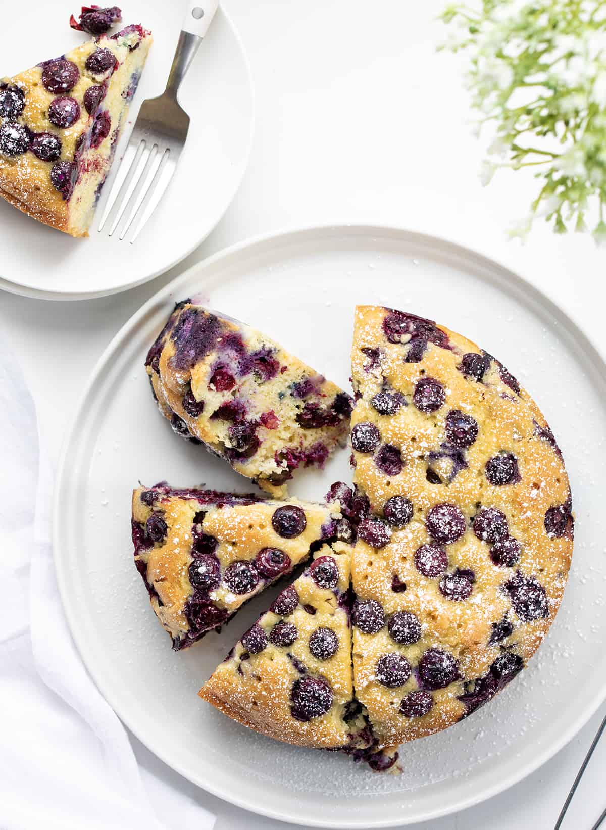 Whole Blueberry Breakfast Cake With Some Pieces Cut and One Piece Removed.