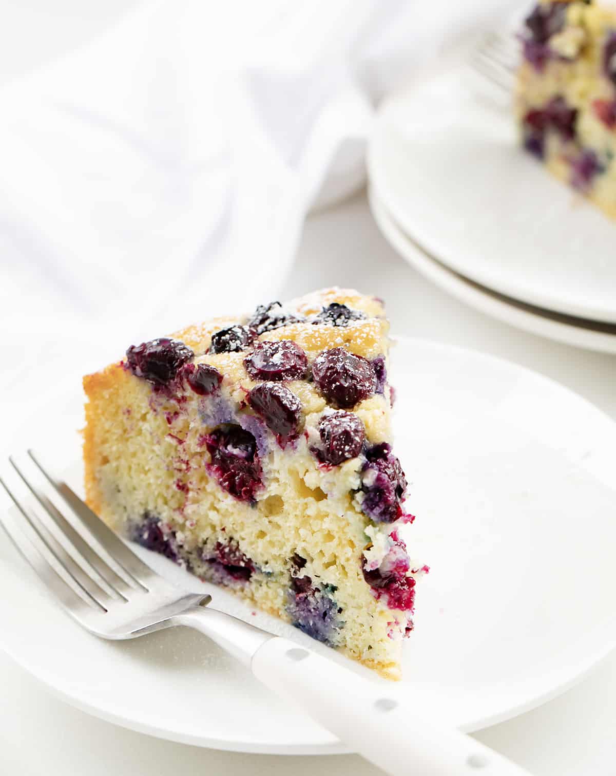 Slices of Blueberry Breakfast Cake on White Plates.
