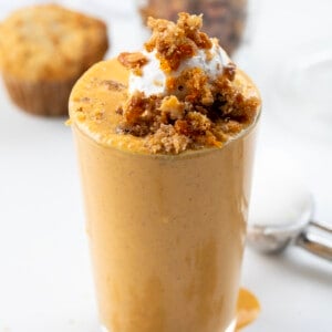 Glass of Carrot Cake Milkshake with Whipped Cream and Crumbled Carrot Cake on Top.