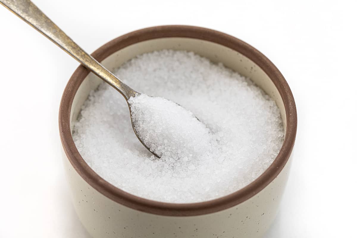 A Container of Sea Salt with a Spoon in it.