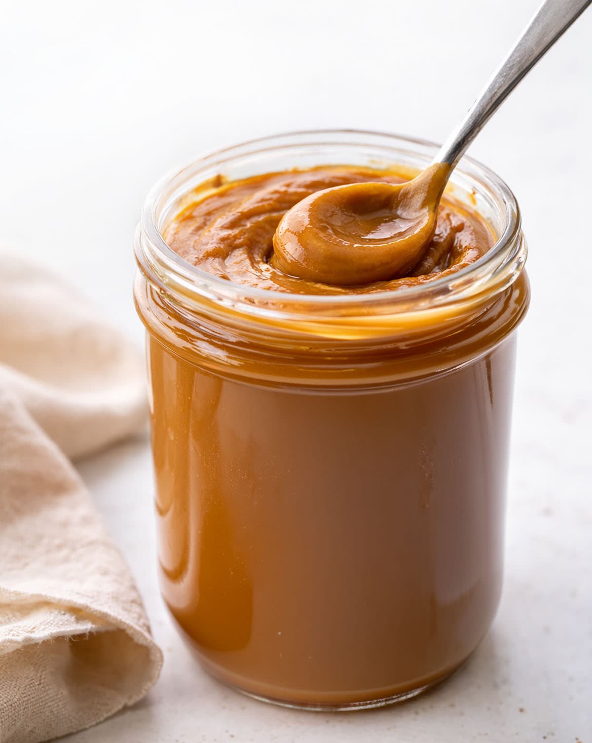 Jar of Dulce de Leche with a full spoon in it.