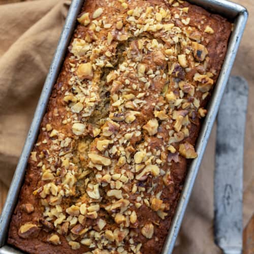 Looking Down Onto Brown Butter Banana Nut Bread on a Cutting Board with a Knife.