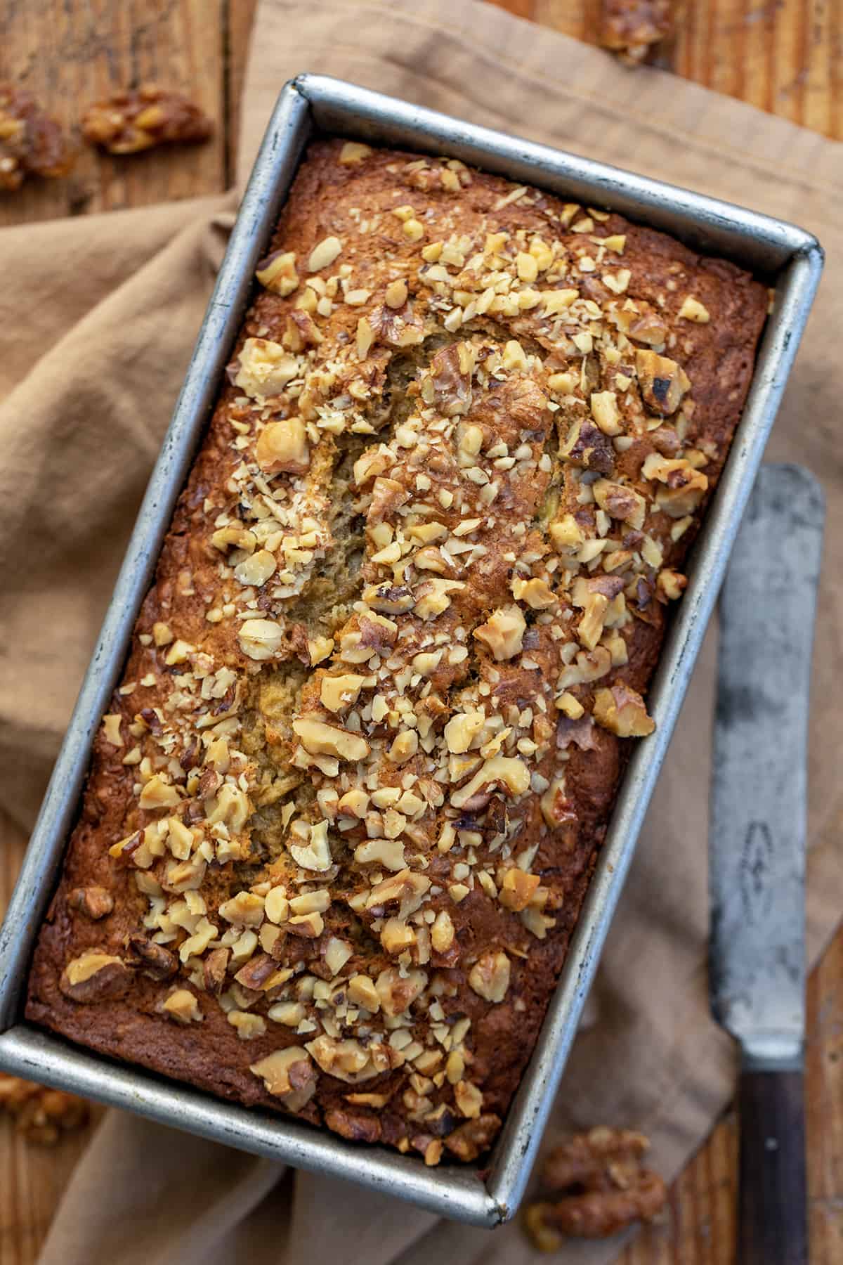 Looking Down Onto Brown Butter Banana Nut Bread on a Cutting Board with a Knife.