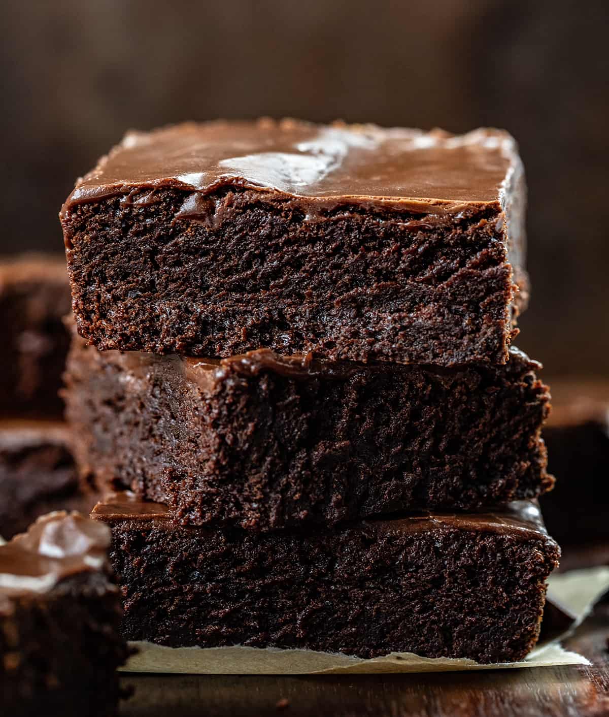 Three Double Fudge Brownies Stacked on Top of Each Other on a Dark Cutting Board.