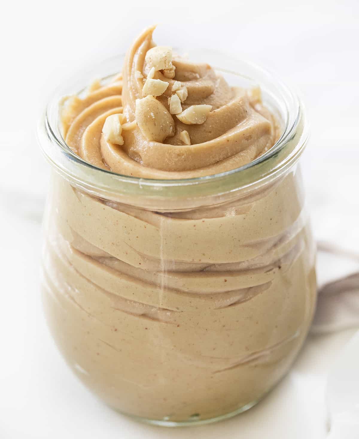 Container of Peanut Butter Mousse Swirled Inside a Jar on a White Counter.