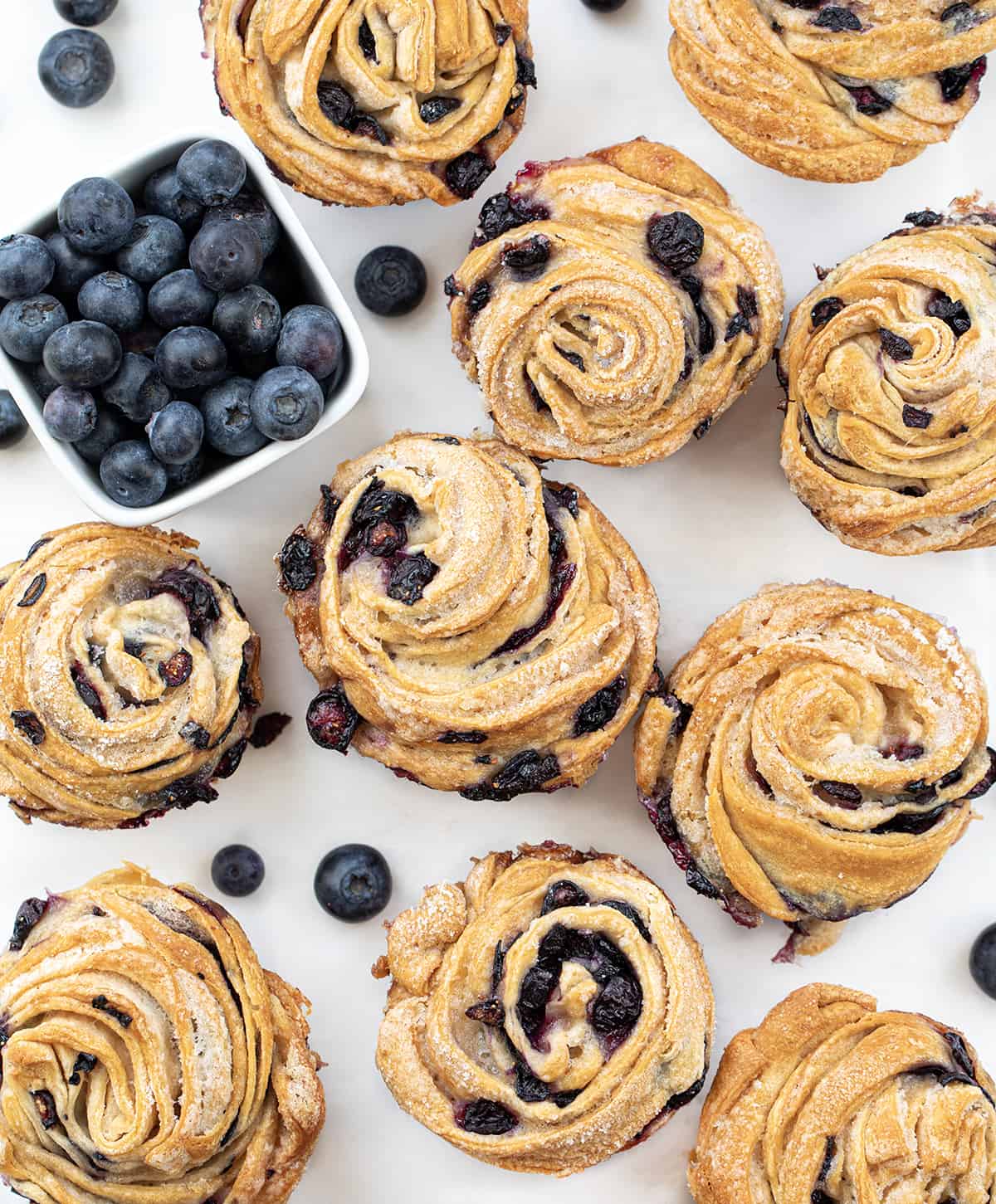 Blueberry Cruffins From Overhead on a White Counter with Fresh Blueberries.