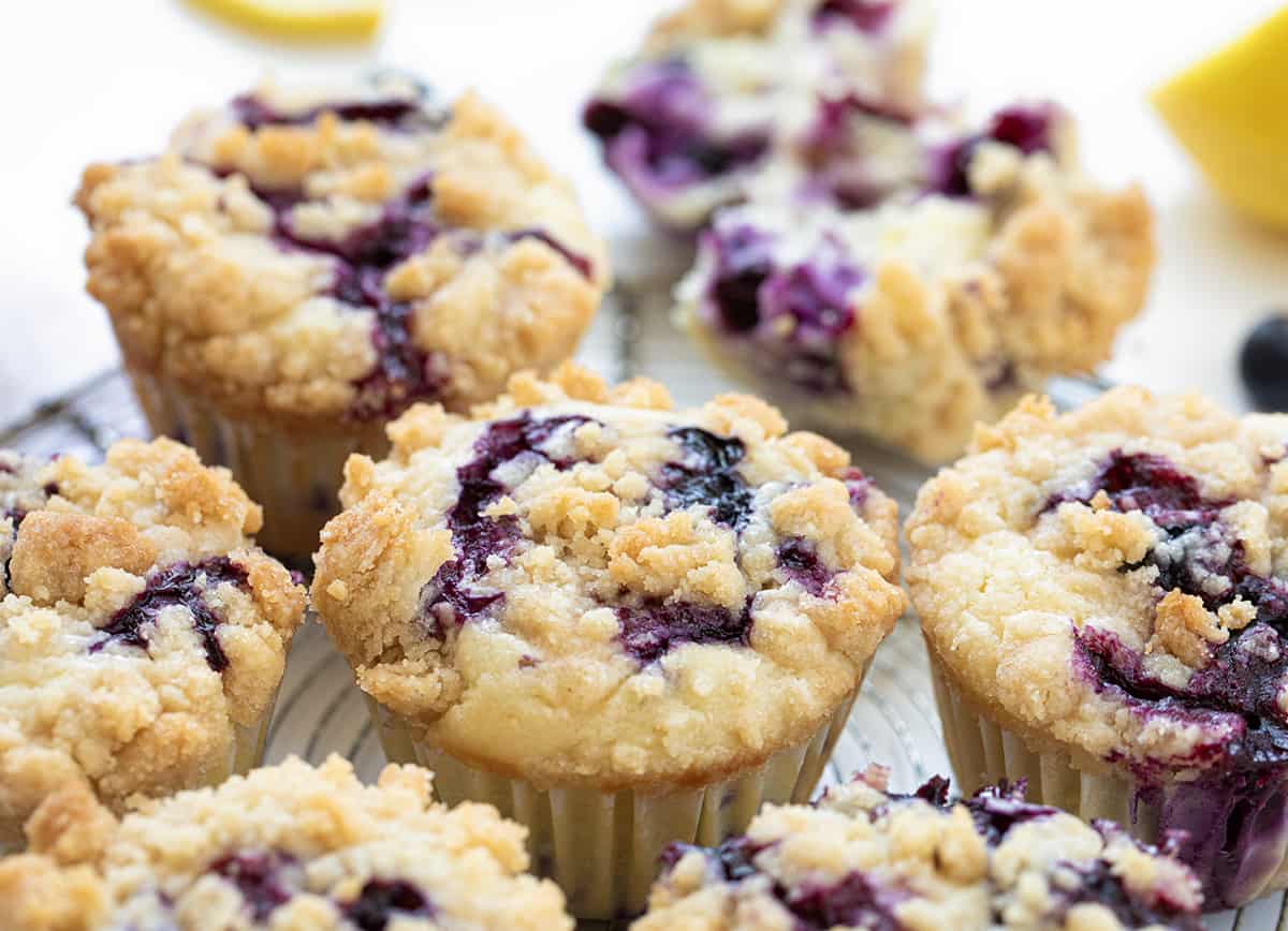 Blueberry Lemon Muffins on a White Counter with Fresh Lemon Slice and Blueberries.