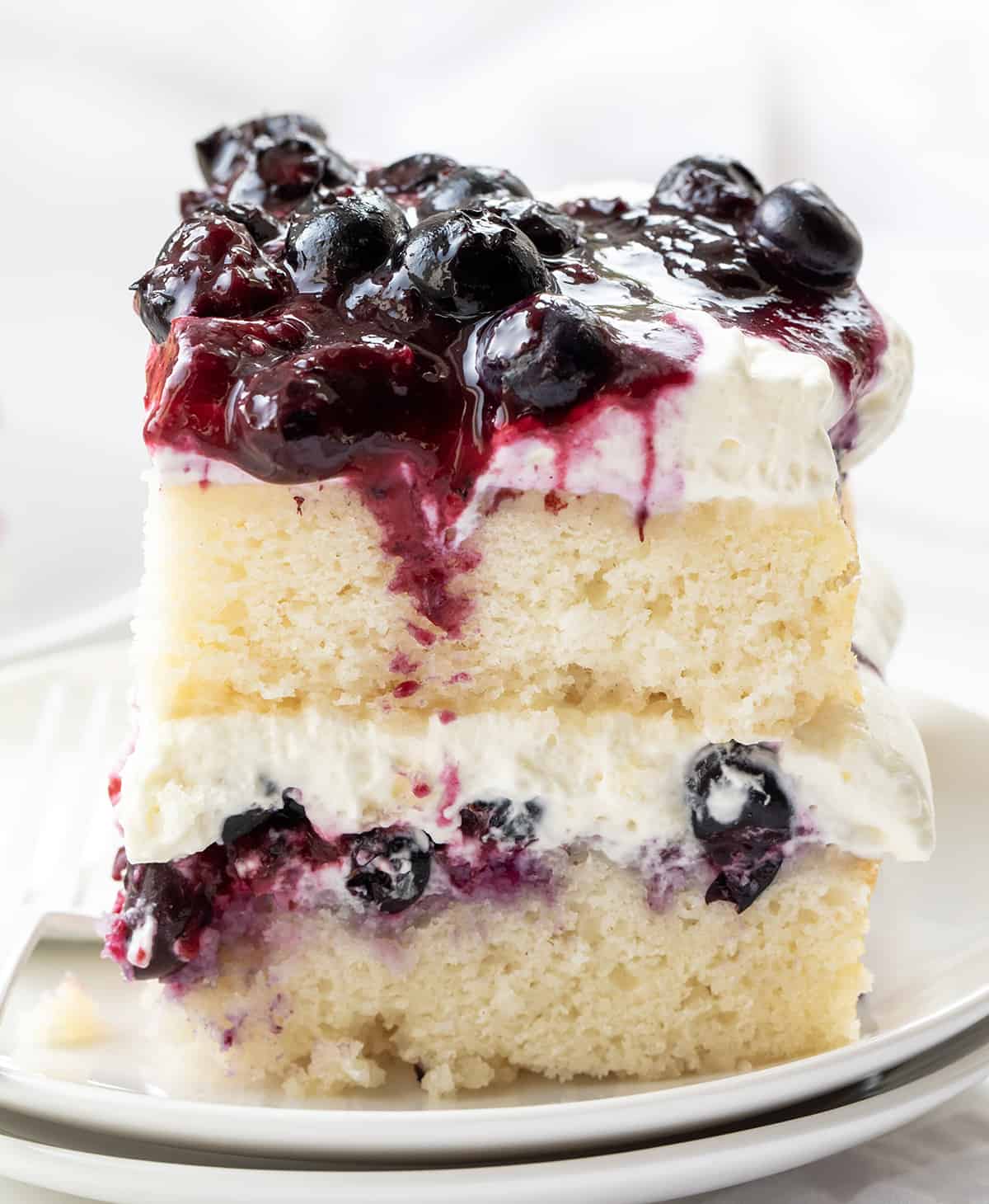 One Piece of Sheet Pan Blueberry Shortcake Cake on a White Plate.