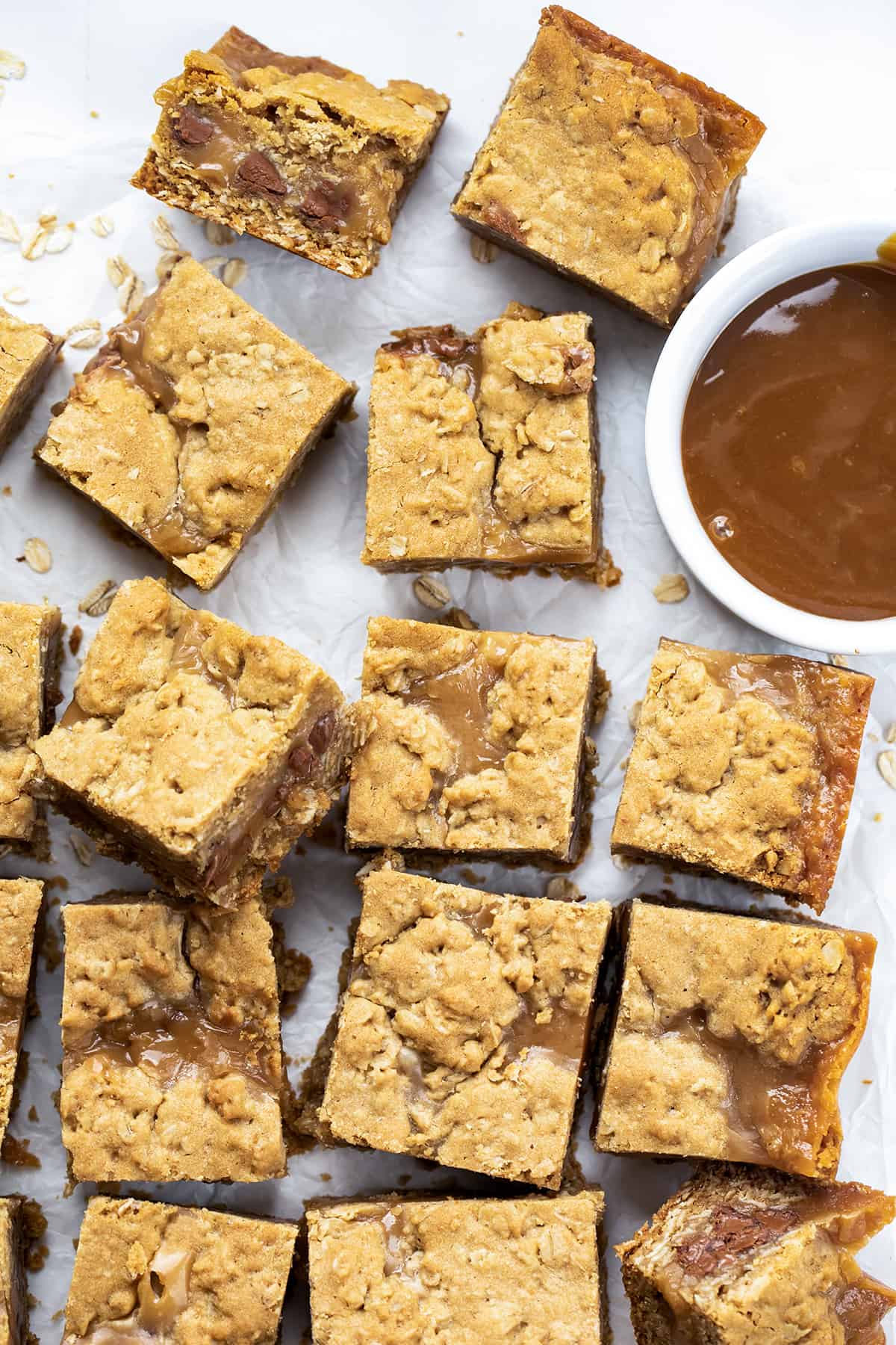 Chocolate Caramel Oatmeal Cookie Bars Cut Up into Individual Pieces but Separated on a Counter with Caramel Sauce.