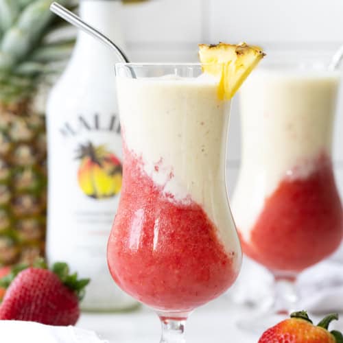 The Lava Flow Drink on a Counter with Pineapple, Malibu, and another Lava Flow Behind It.