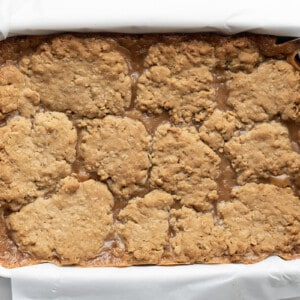 Overhead of Chocolate Caramel Oatmeal Cookie Bars in White Pan on White Counter.