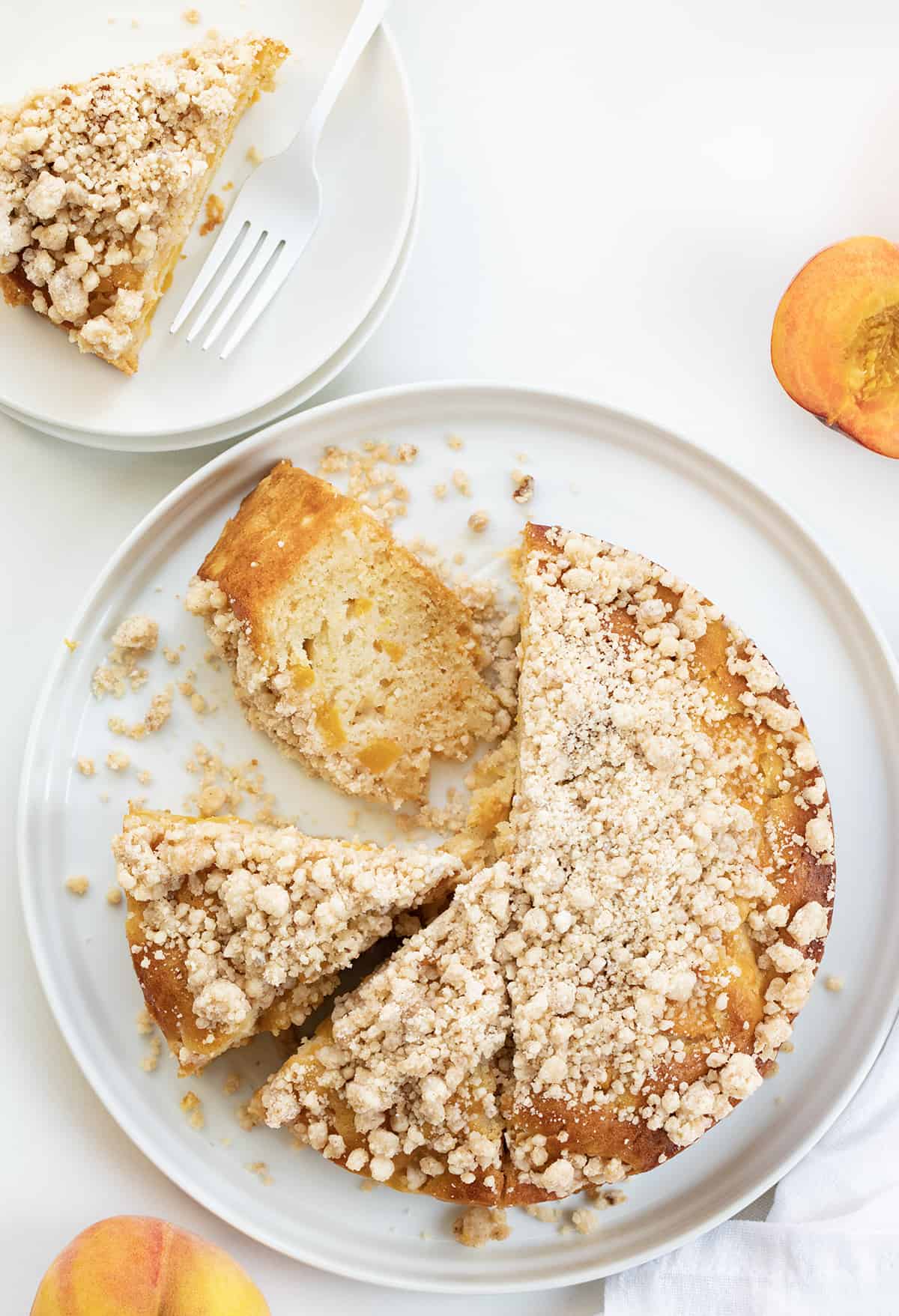 Whole Peach Cake on White Platter With Half of the Pieces Cut and One on its Side.