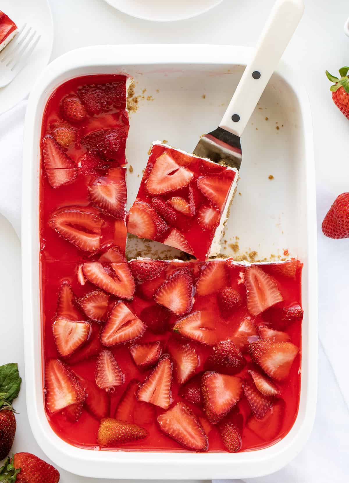 Pan of Strawberry Pretzel Salad Bars With Some Missing and One Piece on a Spatula About to be Removed.