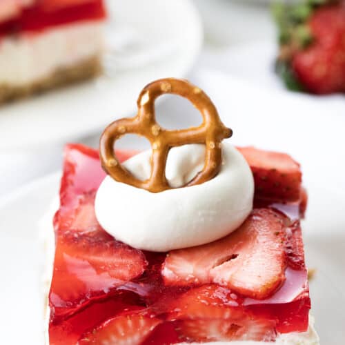 Strawberry Pretzel Salad on White Plates with Strawberries and a Pretzel on Top.