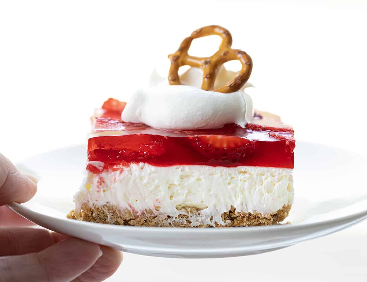 Hand Holding a Plate of Strawberry Pretzel Salad.