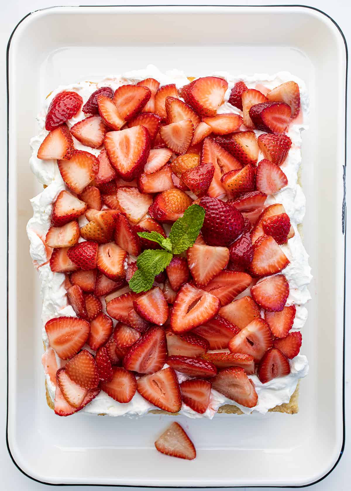 Looking Down onto a Sheet Pan Strawberry Shortcake with a Sprig of Mint in the Middle.