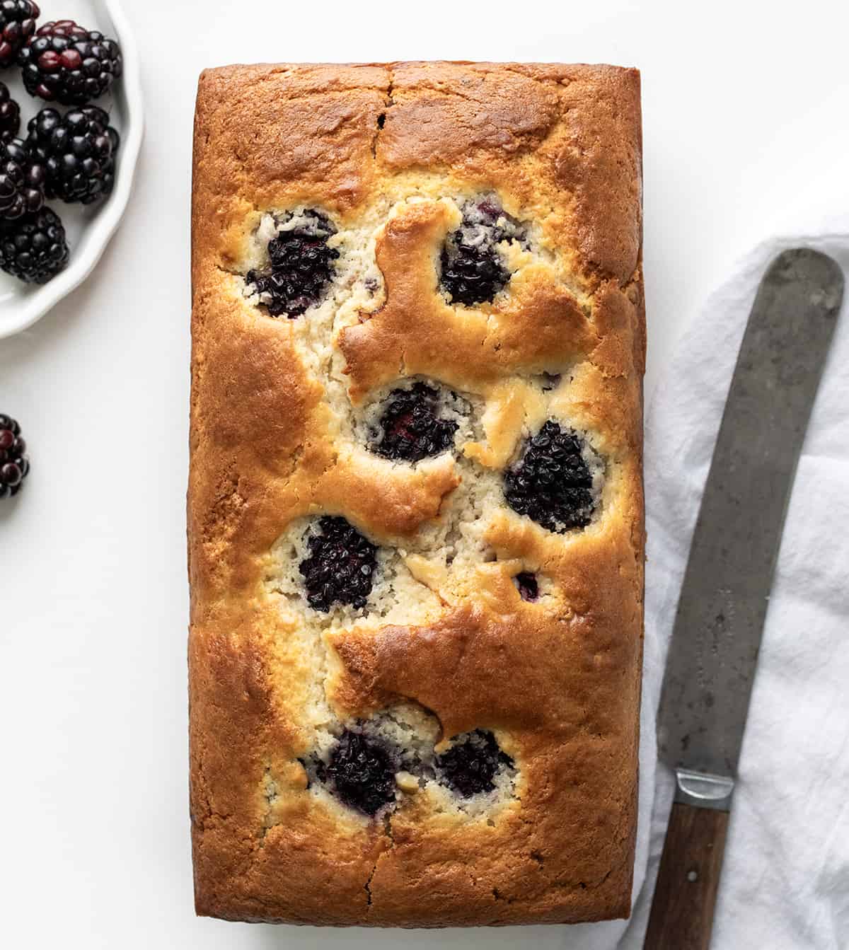 Blackberry Loaf on a White Counter with Blackberries and Knife on a White Towel. 