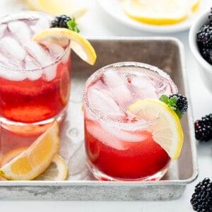 Three Blackberry Moscato Cocktails in a Tray with Lemon Slices and Fresh Blackberry.