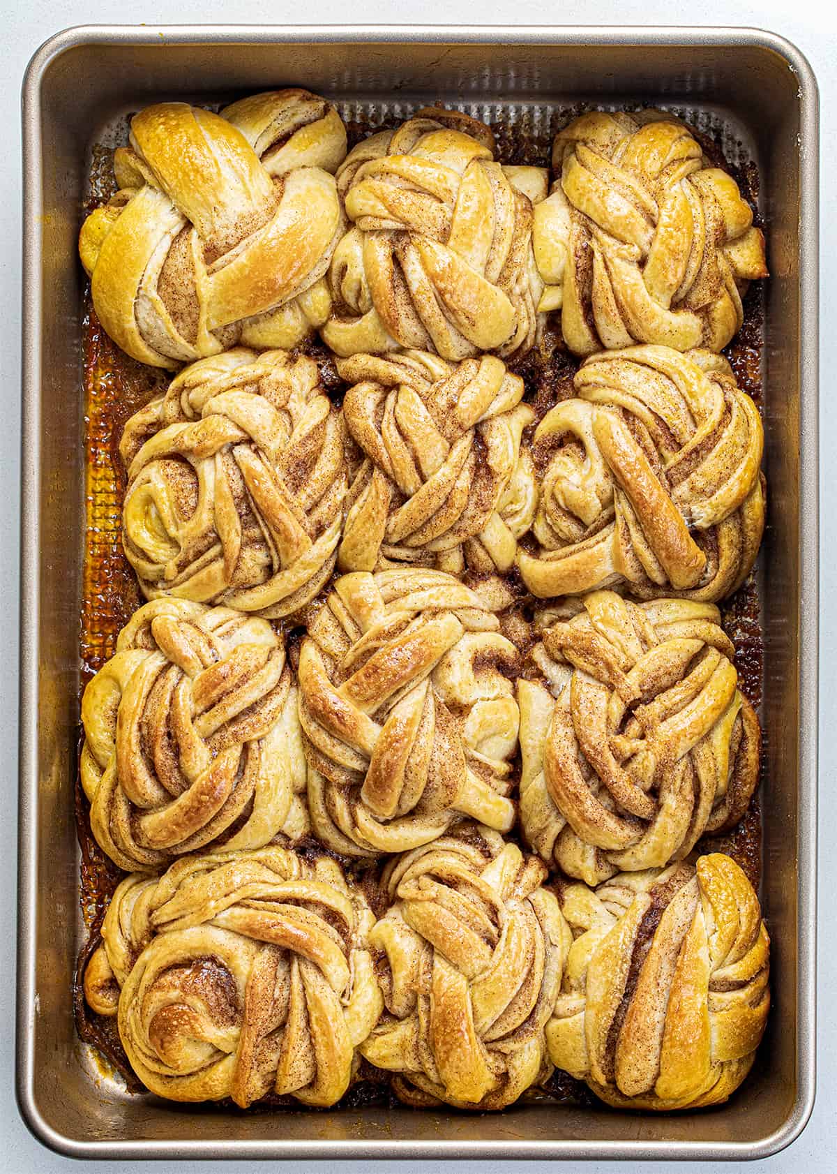 Braided Cinnamon Rolls After Baking in a Pan from Overhead on a White Counter.