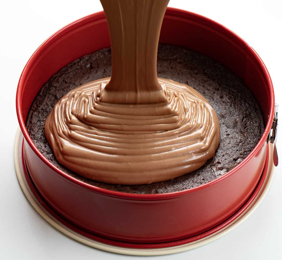 Pouring Chocolate Cheesecake Over Baked Brownie to Make Brownie Bottom Chocolate Cheesecake.