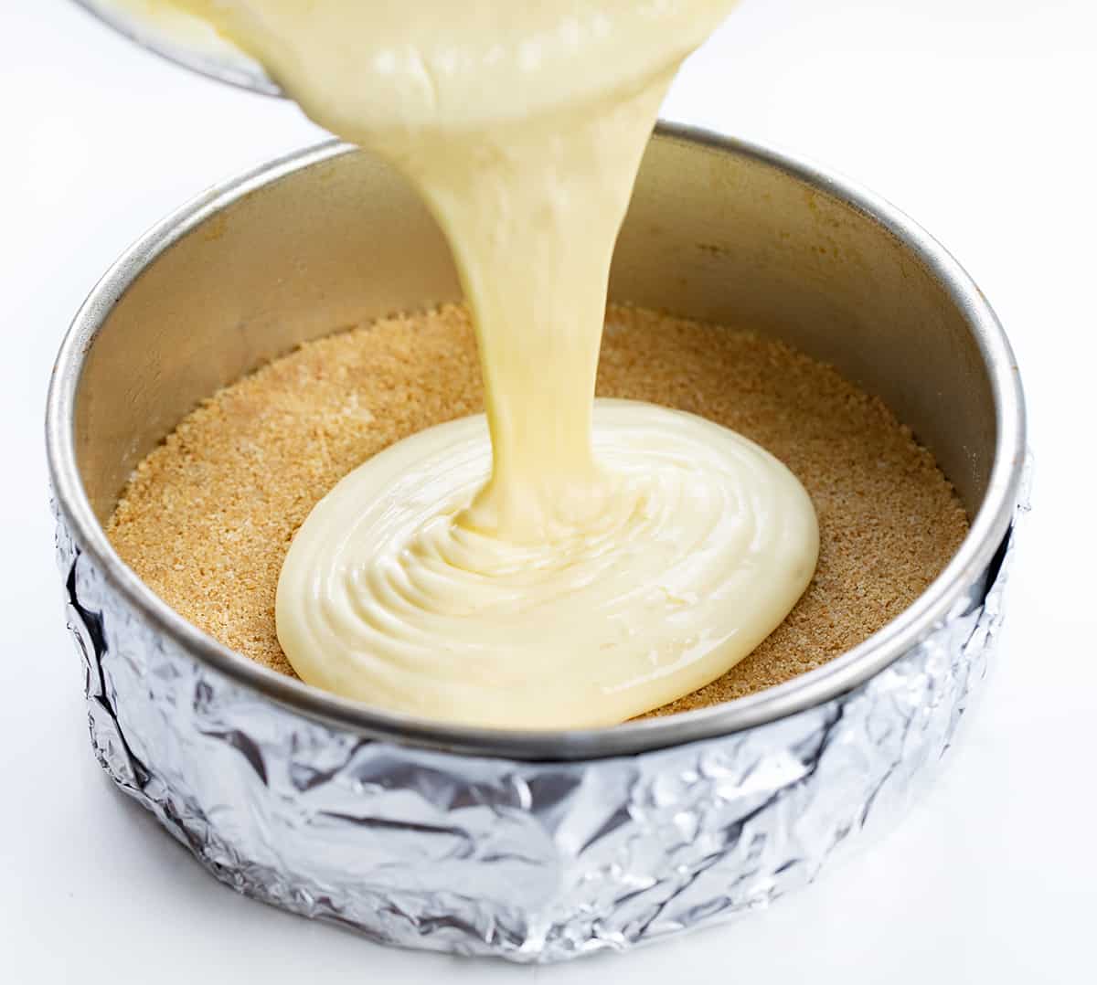 Pouring Lemon Cheesecake Batter into a Pan with Graham Cracker Crust.