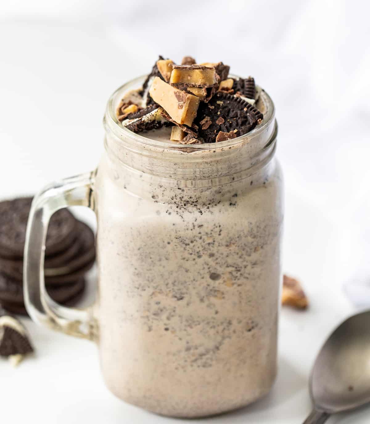 Mug of Oreo Heath Blizzard, a Recipe Adaptation Based on Dairy Queens Blizzard, and Surrounded by Oreos and Heath. 