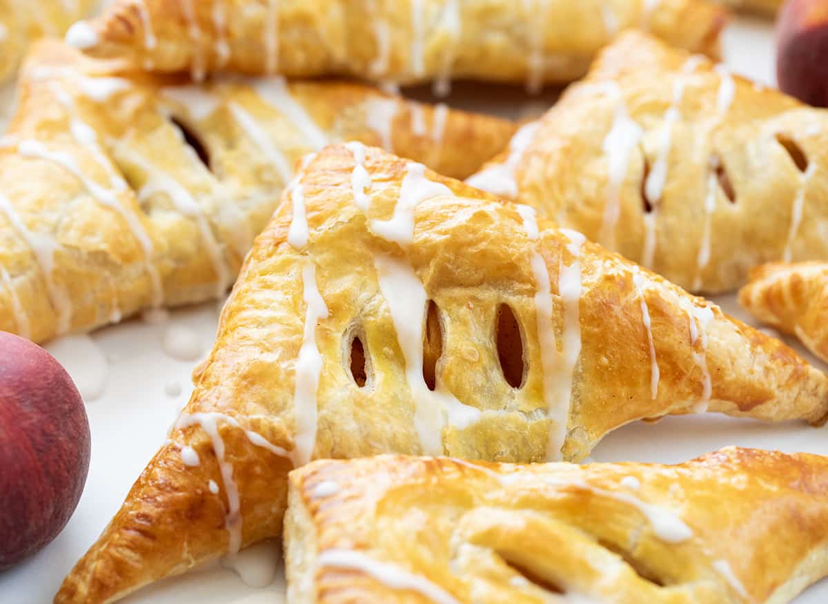 Peach Turnovers on a White Counter with Peaches.