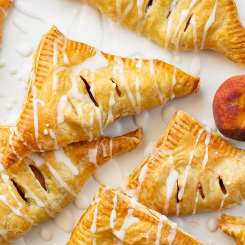 Peach Turnovers on a Piece of White Parchment with Peaches.