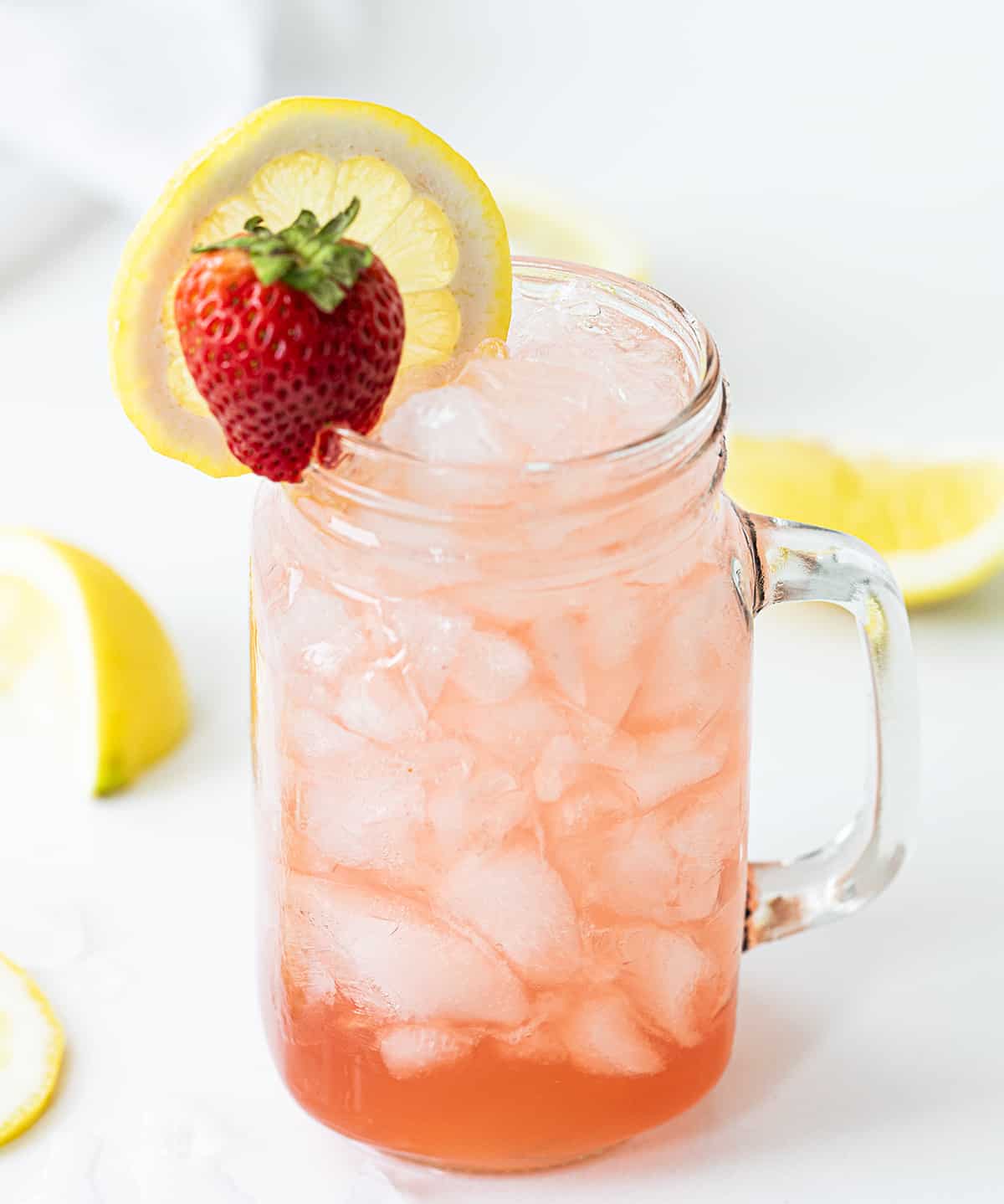 Glass Mug with Whiskey Strawberry Lemonade and a Strawberry and Lemon Garnish. 